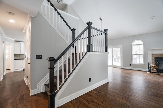 stairs featuring hardwood / wood-style flooring, ornamental molding, and vaulted ceiling