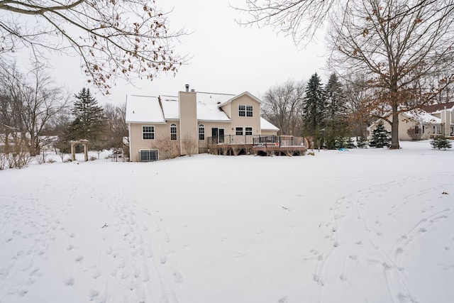 snow covered rear of property featuring central AC and a deck