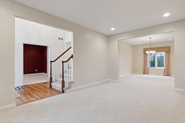 spare room featuring a chandelier, stairway, carpet, and visible vents