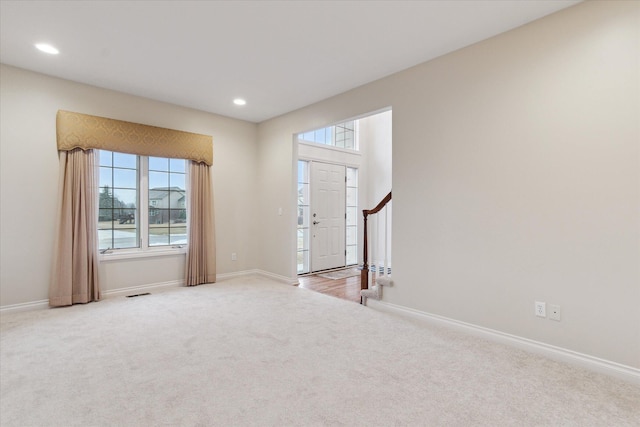 entrance foyer with carpet floors, stairway, plenty of natural light, and baseboards