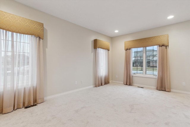 empty room with a wealth of natural light, baseboards, visible vents, and carpet