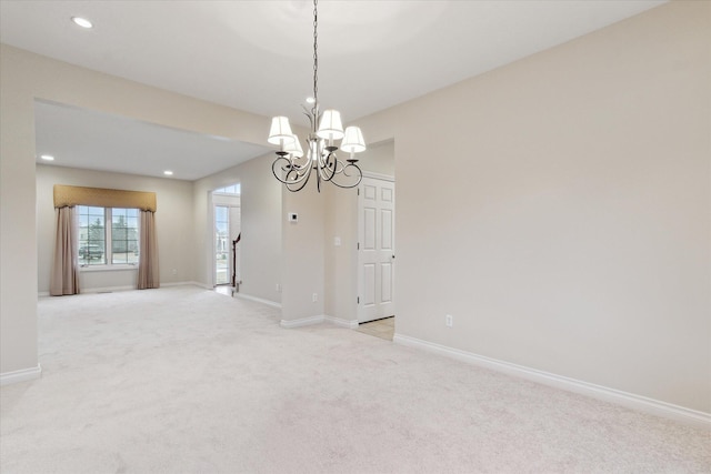 spare room featuring light carpet, recessed lighting, a chandelier, and baseboards