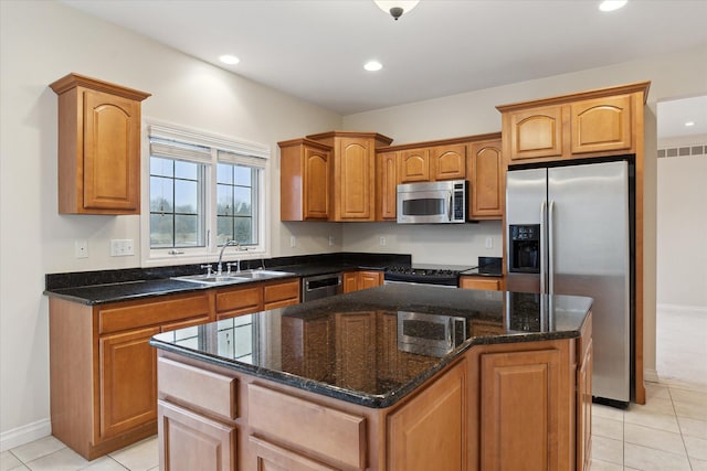 kitchen with stainless steel appliances, light tile patterned floors, a sink, and a kitchen island