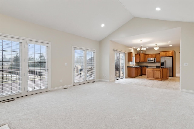 unfurnished living room with visible vents, an inviting chandelier, light carpet, vaulted ceiling, and baseboards