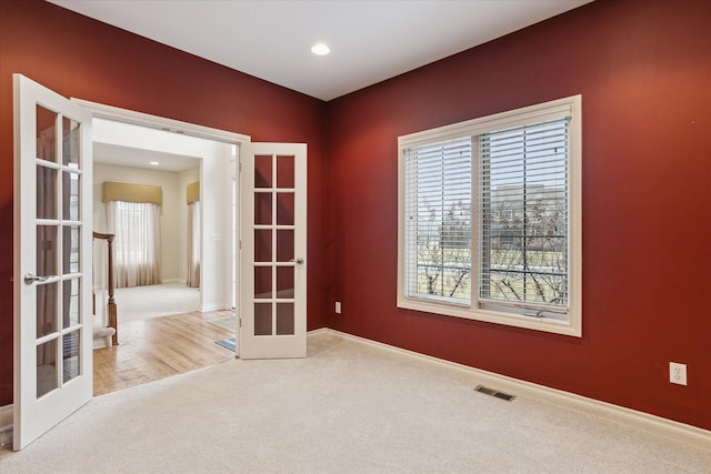 carpeted spare room with french doors, visible vents, and baseboards