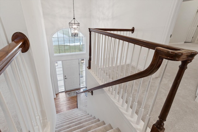 stairway featuring a notable chandelier and a towering ceiling