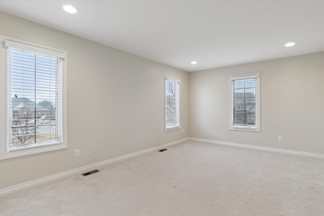 spare room with light colored carpet, recessed lighting, visible vents, and baseboards