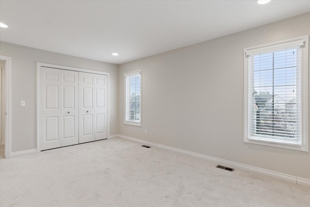 unfurnished bedroom with multiple windows, carpet flooring, visible vents, and baseboards