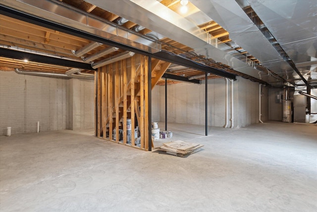 unfinished basement featuring heating unit, brick wall, and gas water heater