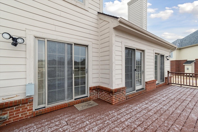 exterior space featuring a deck, brick siding, and a chimney