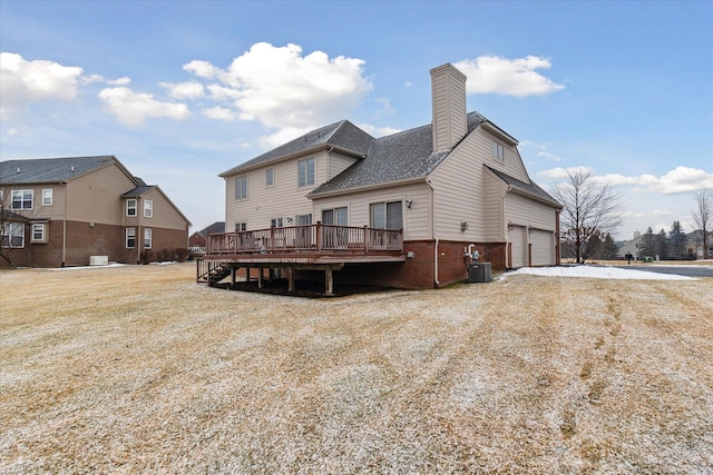 back of house featuring a deck, cooling unit, a garage, brick siding, and a chimney