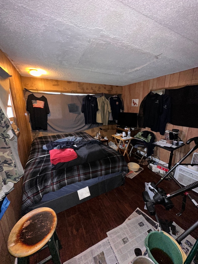 bedroom featuring wooden walls, wood-type flooring, and a textured ceiling