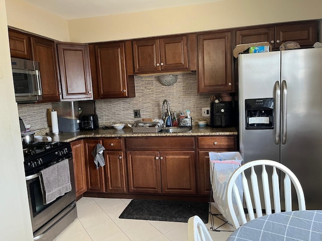 kitchen featuring appliances with stainless steel finishes, tasteful backsplash, dark stone counters, and sink