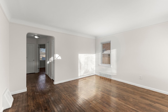 empty room with dark hardwood / wood-style floors and crown molding