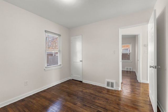 empty room with plenty of natural light and dark wood-type flooring