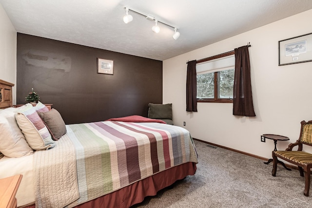 carpeted bedroom featuring track lighting