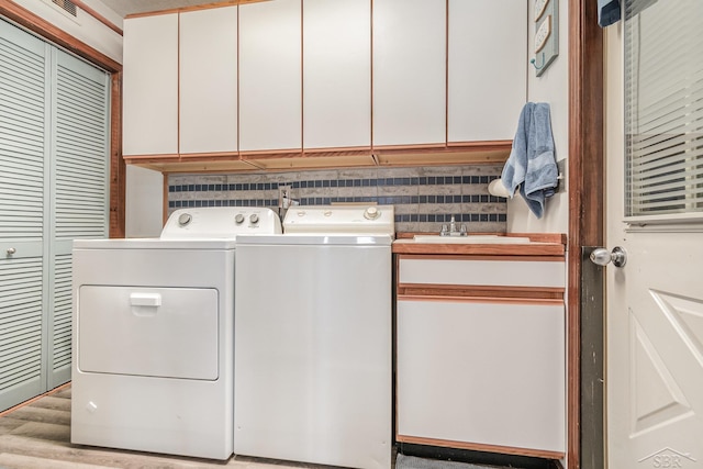 laundry area with cabinets, separate washer and dryer, sink, and light wood-type flooring