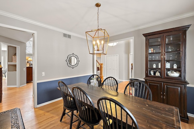 dining area featuring a chandelier, light hardwood / wood-style floors, and ornamental molding