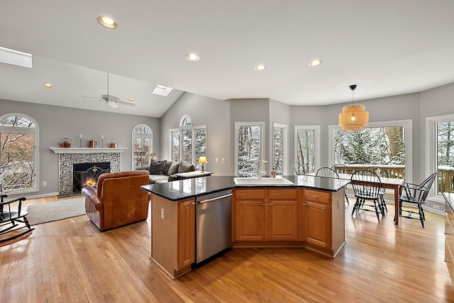 kitchen with dishwasher, a kitchen island, sink, and a tiled fireplace