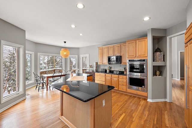 kitchen featuring a kitchen island, light brown cabinetry, decorative light fixtures, light hardwood / wood-style floors, and stainless steel double oven