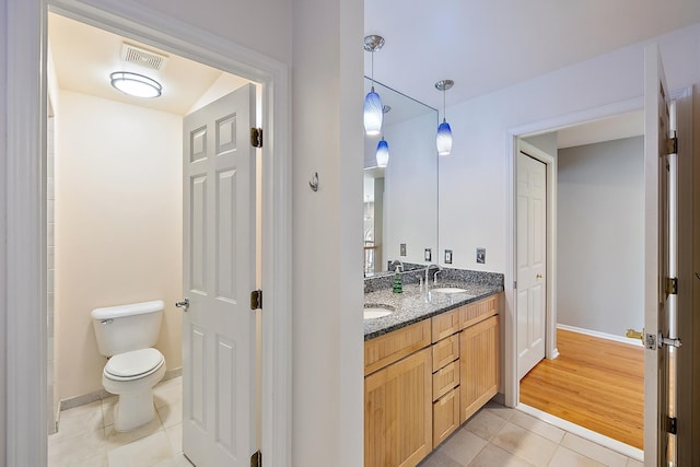 bathroom with toilet, vanity, and tile patterned floors