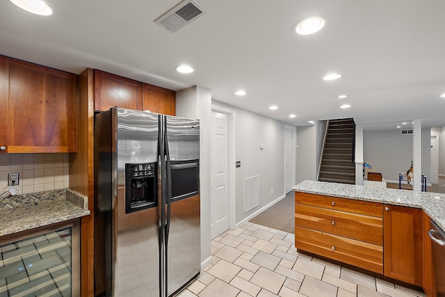 kitchen with decorative backsplash, light tile patterned flooring, light stone counters, and stainless steel refrigerator with ice dispenser