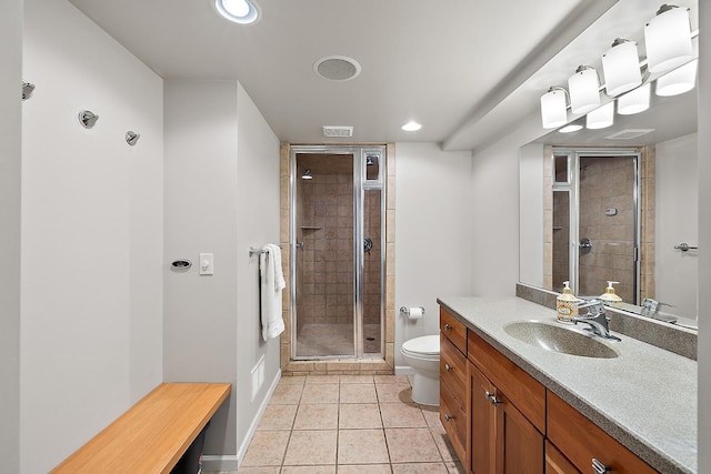 bathroom featuring tile patterned floors, vanity, toilet, and a shower with shower door