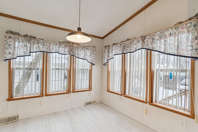 unfurnished room with a textured ceiling, hardwood / wood-style flooring, and vaulted ceiling