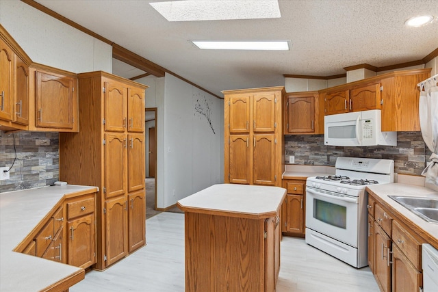 kitchen featuring white appliances, a skylight, a kitchen island, and backsplash