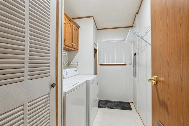 clothes washing area featuring cabinets, ornamental molding, and washing machine and clothes dryer