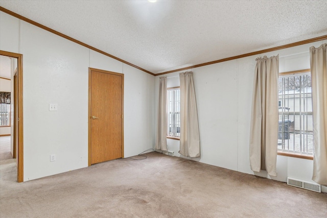 empty room featuring a textured ceiling, light carpet, crown molding, and lofted ceiling