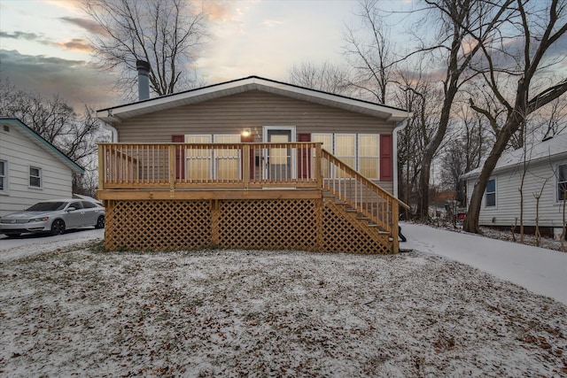 snow covered rear of property featuring a deck