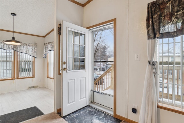 entryway featuring a wealth of natural light, crown molding, and a textured ceiling