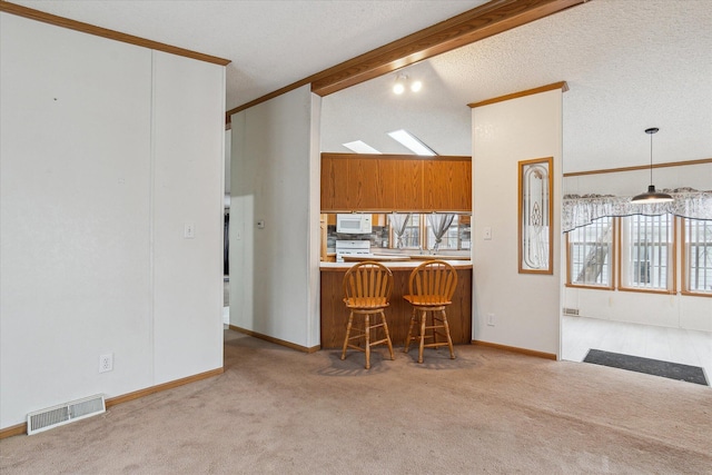 kitchen featuring kitchen peninsula, a breakfast bar, light colored carpet, crown molding, and pendant lighting