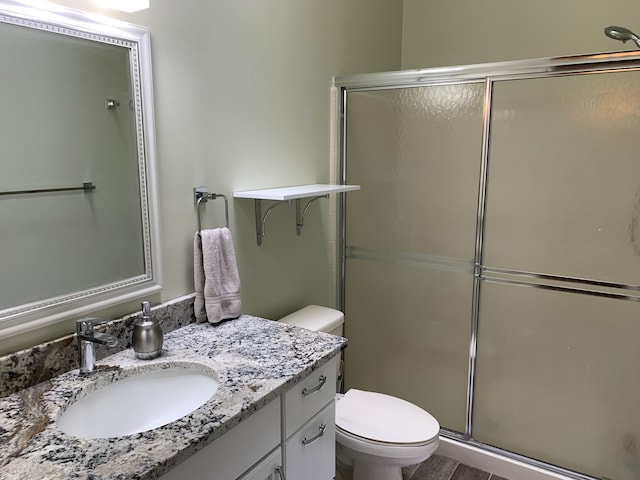 bathroom featuring an enclosed shower, toilet, and vanity