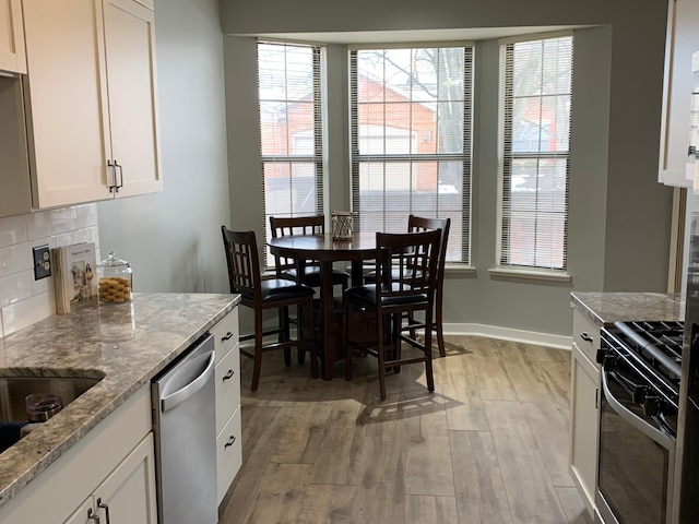 kitchen with range with gas cooktop, dishwasher, light wood-type flooring, decorative backsplash, and white cabinets