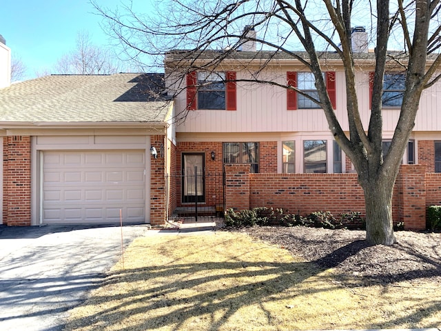 view of front of property featuring brick siding, driveway, a chimney, and a garage