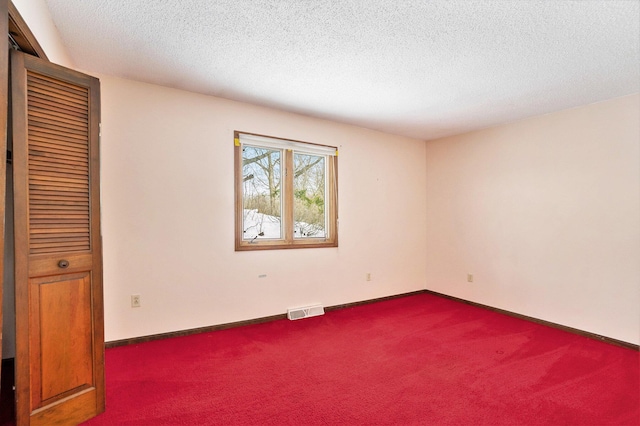 carpeted empty room with a textured ceiling