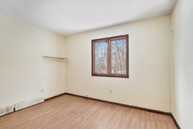 unfurnished room with light hardwood / wood-style flooring and a textured ceiling