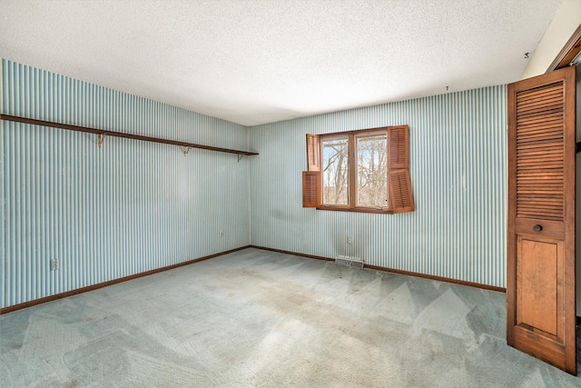 carpeted spare room featuring a textured ceiling