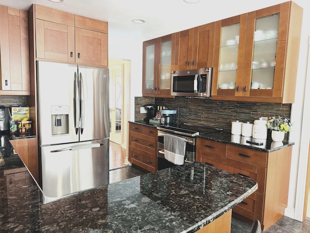 kitchen with backsplash, appliances with stainless steel finishes, and dark stone counters