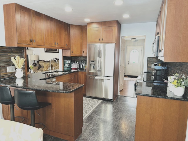 kitchen featuring backsplash, sink, kitchen peninsula, and stainless steel refrigerator with ice dispenser