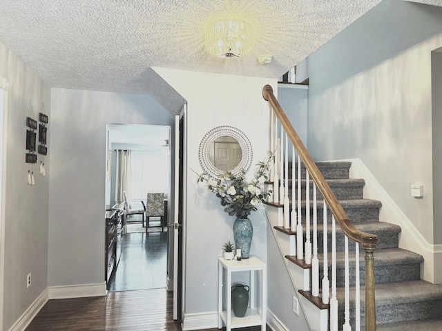 stairs with a chandelier, hardwood / wood-style floors, and a textured ceiling