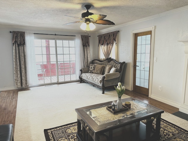 living room featuring ceiling fan, ornamental molding, a textured ceiling, and dark wood-type flooring