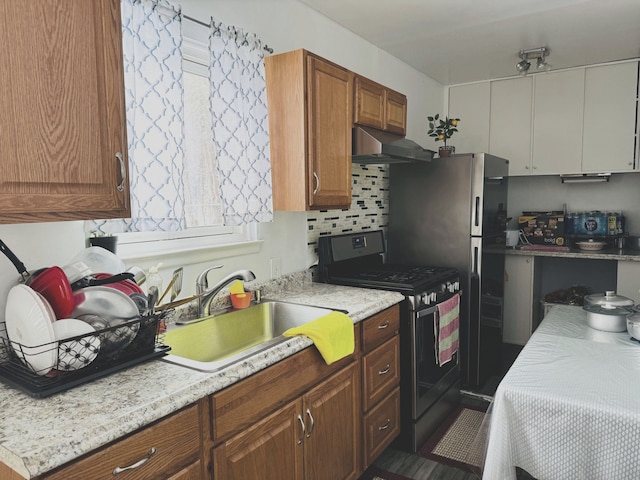 kitchen featuring decorative backsplash, gas stove, and sink