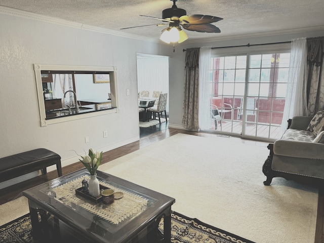 living room featuring ceiling fan, hardwood / wood-style flooring, a textured ceiling, and ornamental molding