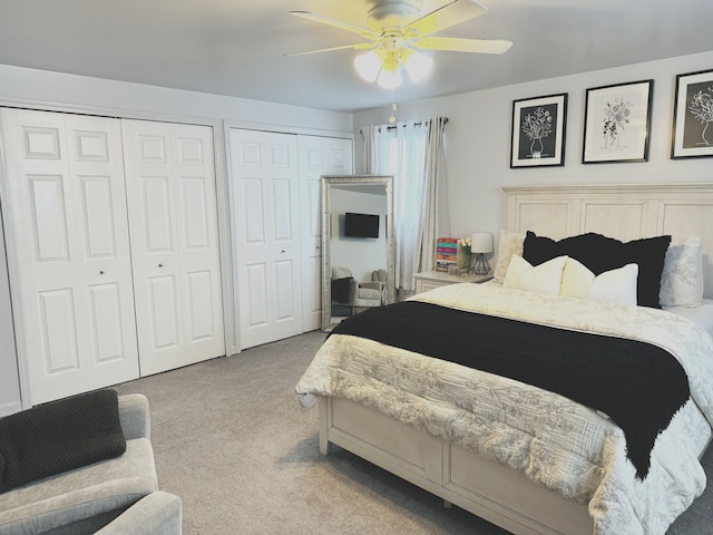 bedroom featuring multiple closets, ceiling fan, and light colored carpet