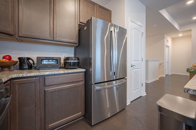 kitchen with stainless steel fridge, light stone countertops, dark hardwood / wood-style floors, and range