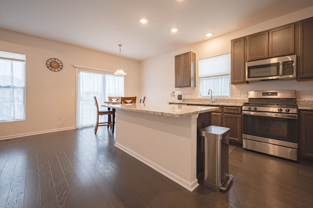 kitchen featuring a wealth of natural light, a center island, hanging light fixtures, and appliances with stainless steel finishes