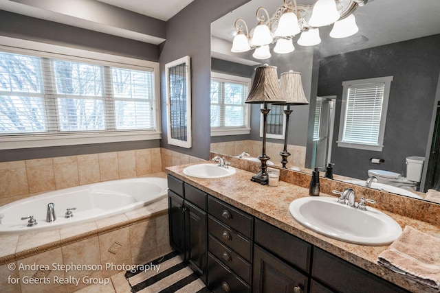 bathroom with a bath, double vanity, a sink, and toilet